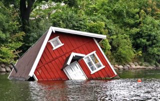 Flooded home sinking into a creek.