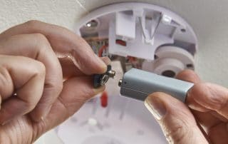 Person changing battery in smoke detector