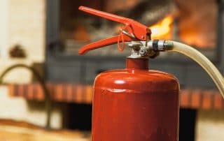 Fire and safety. Fire extinguisher stands in front of fireplace