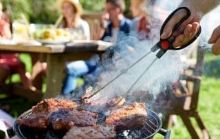 Man cooking meat on barbecue grill at summer party
