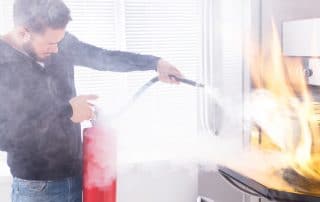 Man using extinguisher to put out oven fire