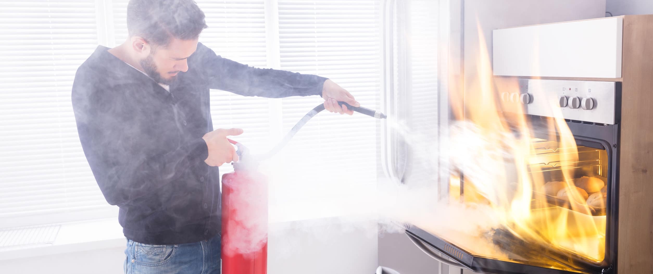 Man using extinguisher to put out oven fire