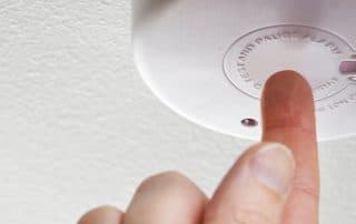 Closeup of hand testing home smoke detector
