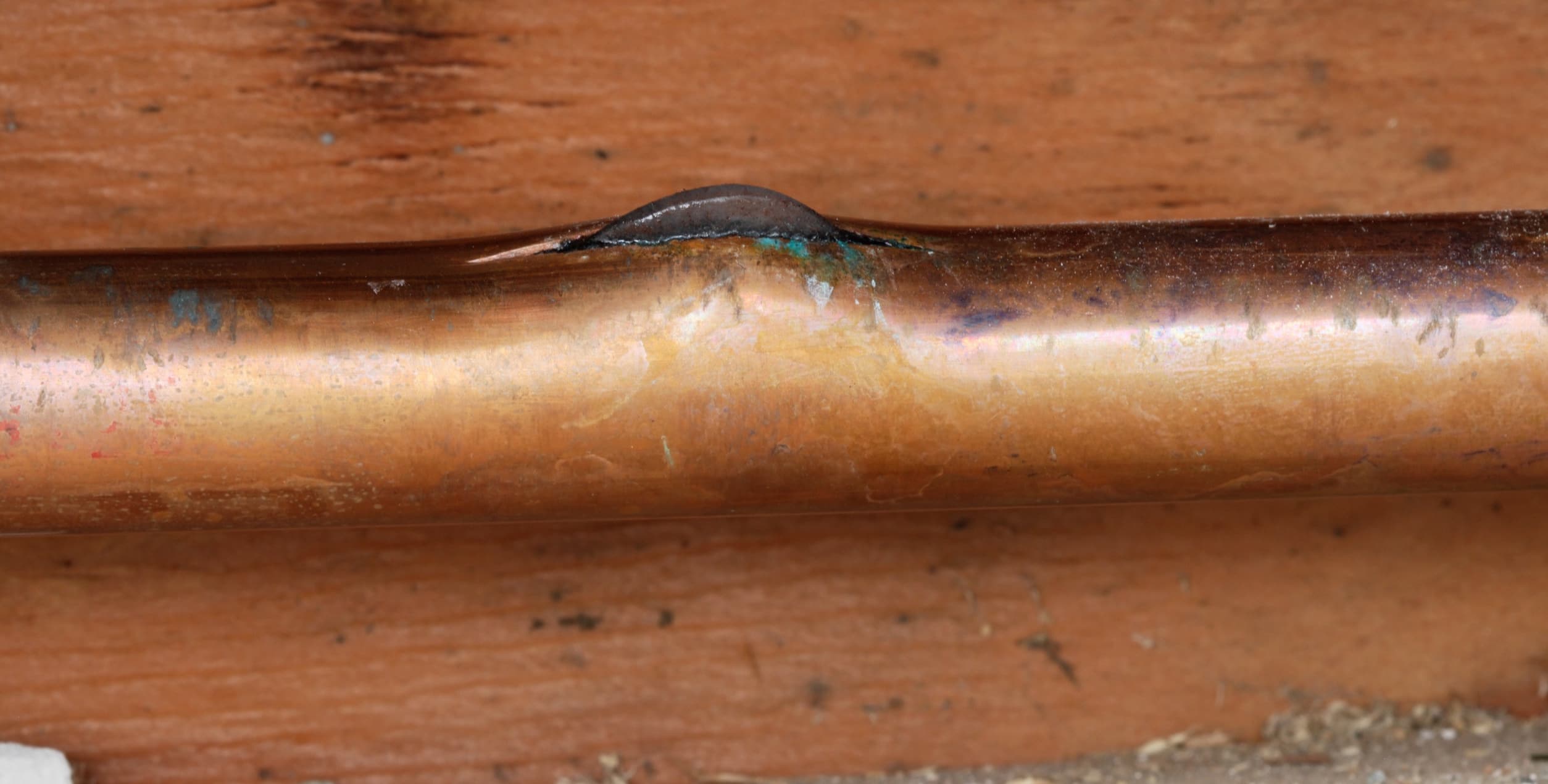 frozen and cracked copper water pipe with ice pushing out of the crack