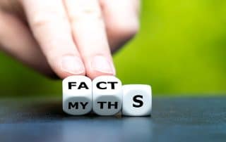 Hand turns dice to change word myths to facts