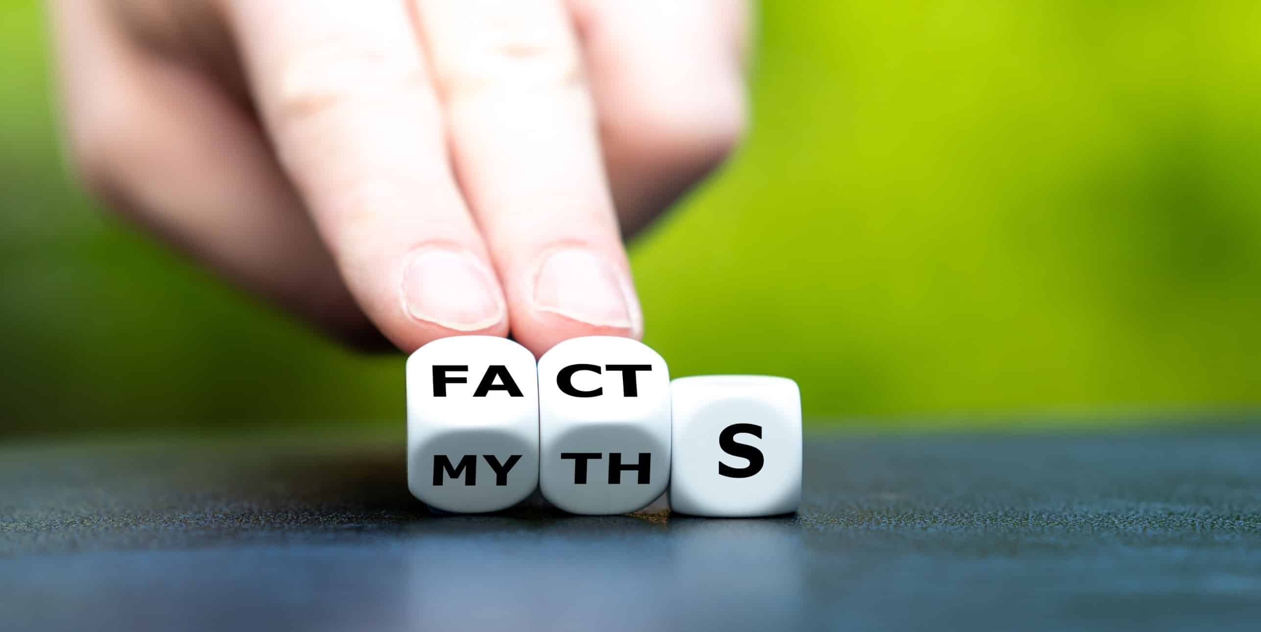 Hand turns dice to change word myths to facts