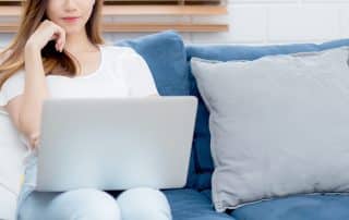 Woman sitting on a couch in a living room looking at a laptop